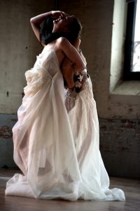 deux mannequins, dos à dos, bras accrochés entre eux et tête renversée portant chacune une robe : une tout en étamine de lin plissée et froissée, l'autre en crochet cuir et coton pour le bustier et étamine de lin plissée pour le bas - séance photo par Dylan des robes de l'exposition "à mains croisées"